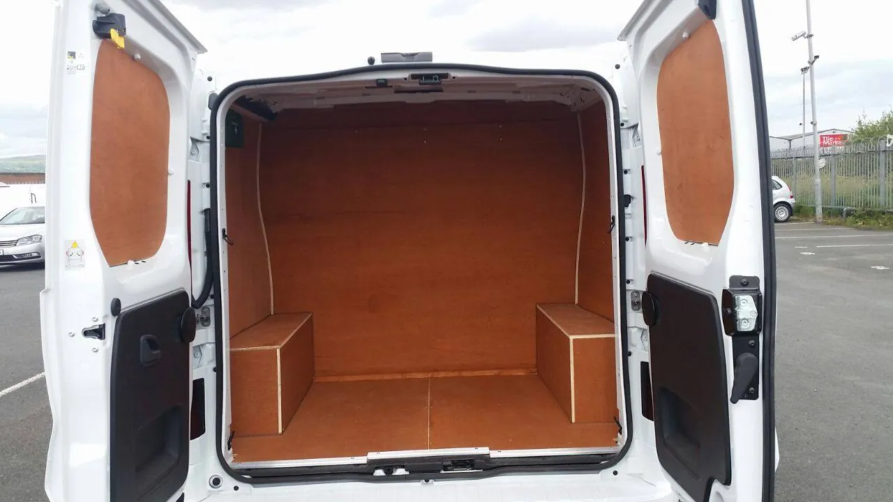 Rear of a white van with a plywood-lined load area and wheel arch boxes